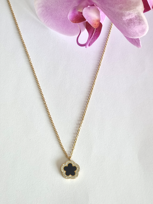 Ce collier Flore noir est un magnifique ajout à ta garde-robe! La fleur en émaille sertie de strass donne un look unique et audacieux qui sublimera ton style.