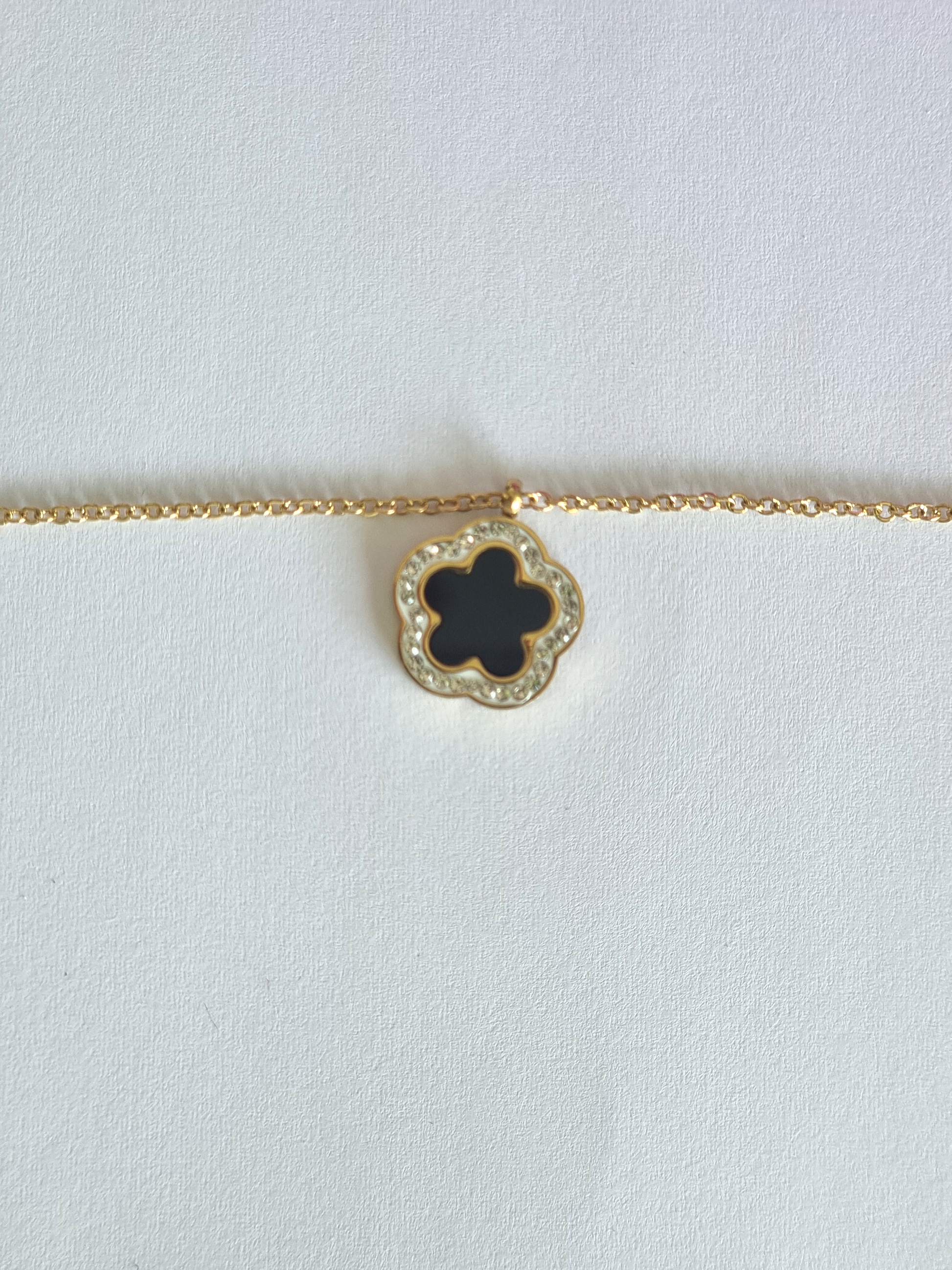 Ce collier Flore noir est un magnifique ajout à ta garde-robe! La fleur en émaille sertie de strass donne un look unique et audacieux qui sublimera ton style.